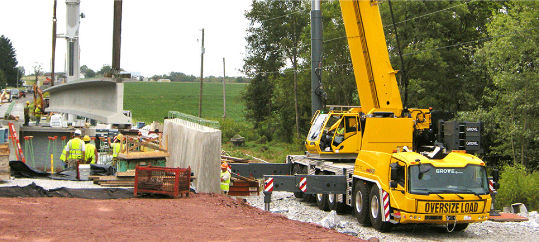  Crane lifting cement beam on a road project 