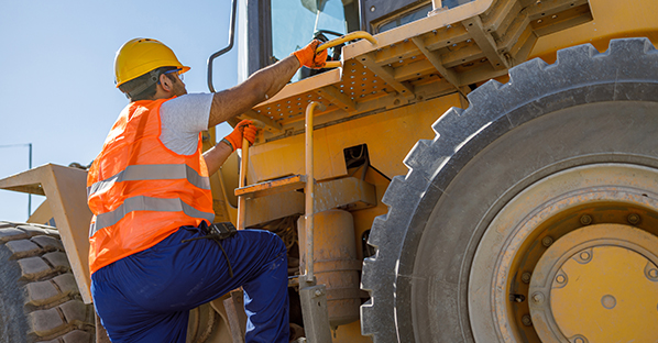 Man climbing up onto a machine at an equipment dealer
